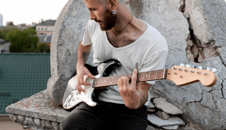 Persona tocando una guitarra acústica al aire libre