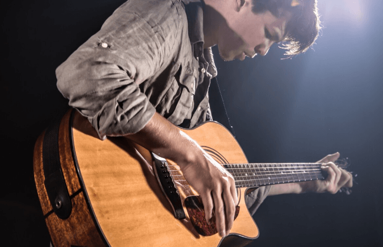 Persona practicando con guitarra acústica en casa
