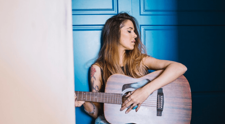 Manos sobre el diapasón de una guitarra acústica