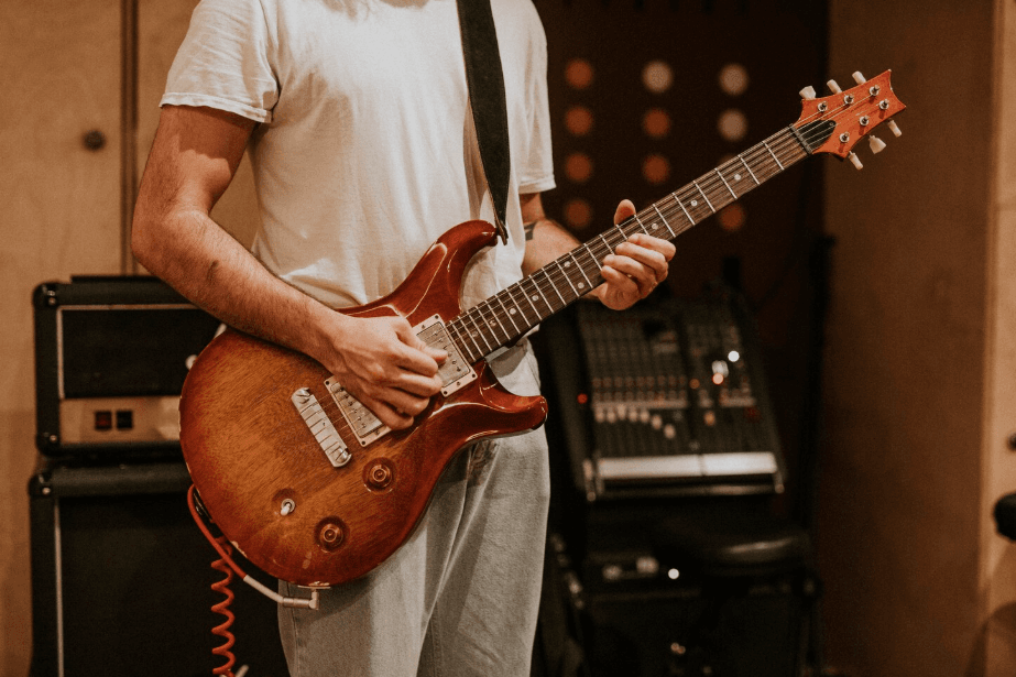 Guitarrista tocando una eléctrica sunburst en un estudio de ensayo
